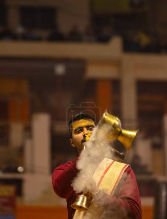 Téléchargez les photos : Varanasi, Uttar Pradesh, India - January 18 2024: Ganga aarti, Portrait of young male priest performing holy river ganges evening aarti at dashashwamedh ghat in traditional dress with hindu rituals. - en image libre de droit