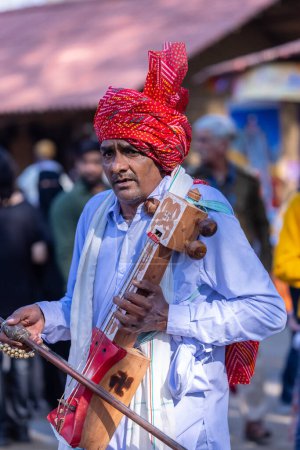 Photo for Faridabad, Haryana, India - February 17 2024: Portrait of male folk artist of haryana playing musical instrument during surajkund craft fair to entertain tourists. - Royalty Free Image