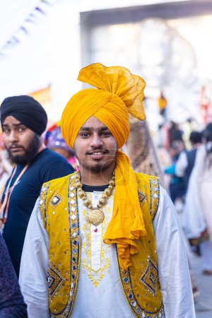 Photo for Faridabad, Haryana, India - February 17 2024: Portrait of a male sikh bhangra artist in traditional colorful dress and jewellery at surajkund crafts fair before they waiting for their performance. - Royalty Free Image