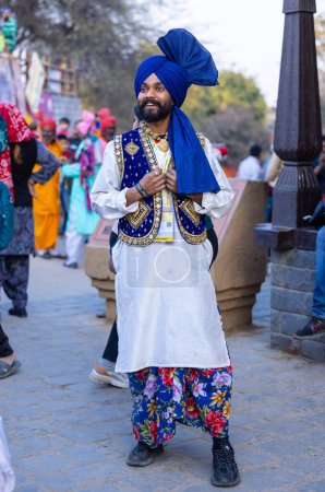 Foto de Faridabad, Haryana, India - February 17 2024: Portrait of a male sikh bhangra artist in traditional colorful dress and jewellery at surajkund crafts fair before they waiting for their performance. - Imagen libre de derechos