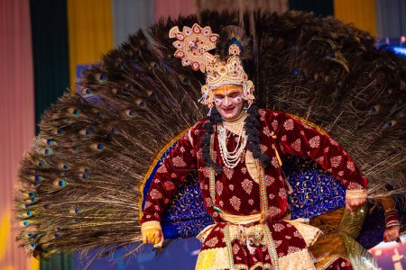 Foto de Ghaziabad, Uttar Pradesh, India - 17 de marzo de 2024: Retrato de un joven artista masculino jugando phoolo ki holi como lord krishna con plumas de pavo real en la espalda durante el festival de holi con ropa étnica colorida. - Imagen libre de derechos
