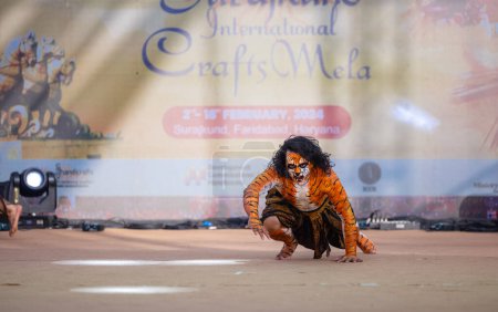 Photo for Faridabad, Haryana, India - February 17 2024: Portrait of an male artist performing classical dance kuchipudi as tiger to save himself from hunter on stage with tiger makeup on his face and body. - Royalty Free Image