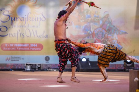 Foto de Faridabad, Haryana, India - 17 de febrero de 2024: Retrato de artistas masculinos del sur de la India realizando danza clásica kuchipudi como cazador y tigre en el escenario con ropa étnica durante la feria de artesanía surajkund. - Imagen libre de derechos