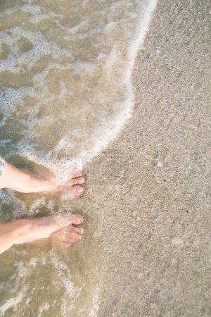 Foto de La edad media de los pies de la mujer de pie en la arena de la playa del océano durante las vacaciones o vacaciones con espacio para copiar - Imagen libre de derechos