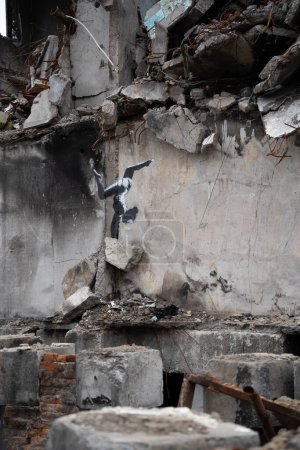 Foto de Borodyanka, región de Kiev 11.12.2022 La obra del mural del artista callejero británico Banksy en la pared de una casa destruida después de la invasión de Rusia en Ucrania. Chica gimnasta de pie en sus manos - Imagen libre de derechos