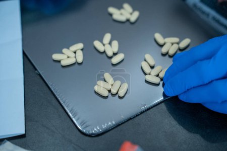 Téléchargez les photos : Les comprimés pour le traitement sont soigneusement disposés sur une table noire dans le laboratoire - en image libre de droit