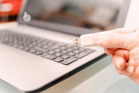 Téléchargez les photos : Close-up of a man using a USB stick connected to a laptop. The USB stick is a security risk - en image libre de droit