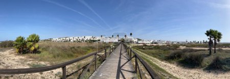 Foto de Panorama desde un paseo marítimo de madera desde la playa hasta la ciudad Conil de la Frontera desde Torre de Guzmán en España - Imagen libre de derechos