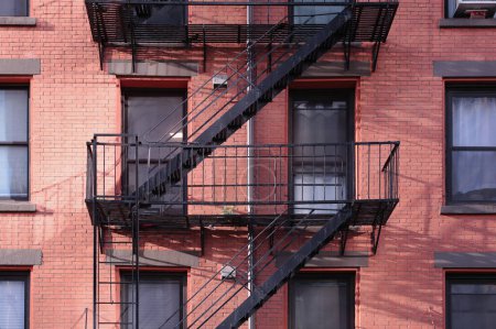 Téléchargez les photos : Fermer l'immeuble d'appartements de New York extérieur en brique rouge peint, fenêtres et escaliers d'évacuation d'incendie en diagonale - en image libre de droit