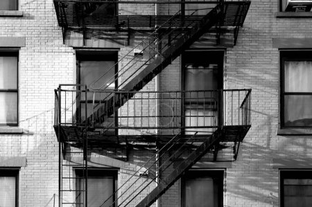 Téléchargez les photos : Noir et blanc fermer New York City immeuble d'appartements avec brique extérieure, fenêtres et diagonale escalier de secours - en image libre de droit