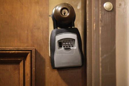 Téléchargez les photos : Boîte de serrure à clé combinée suspendue à une vieille poignée de porte d'appartement en bois - en image libre de droit