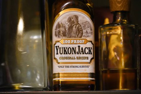 Téléchargez les photos : New York, NY - 10 avril 2023 : Yukon Jack honey whisky liqueur bottle label closeup on bar shelf - en image libre de droit