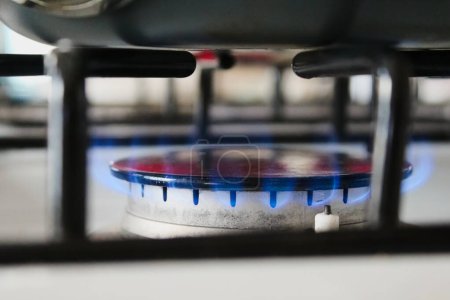 Téléchargez les photos : Utilisation des services publics de gaz naturel sur la cuisinière chauffage d'une casserole avec des flammes bleues - en image libre de droit