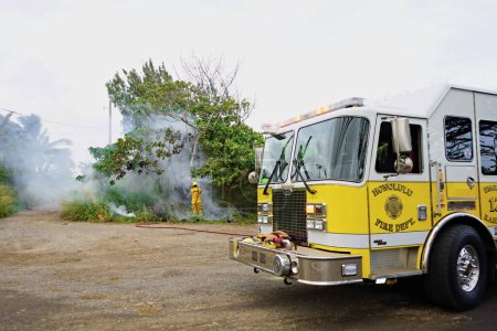 Foto de Kahuku, HI - 3 de enero de 2024: Motor 13 Los bomberos de Kahuku responden con una manguera de incendios forestales en Oahu, Hawaii. Supuestamente, el incendio fue intencionalmente provocado según testigos locales. - Imagen libre de derechos