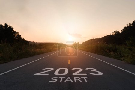 Happy new year 2023,2023 symbolizes the start of the new year. The letter start new year 2023 on the road in the nature route roadway sunset have tree environment ecology or greenery wallpaper concept