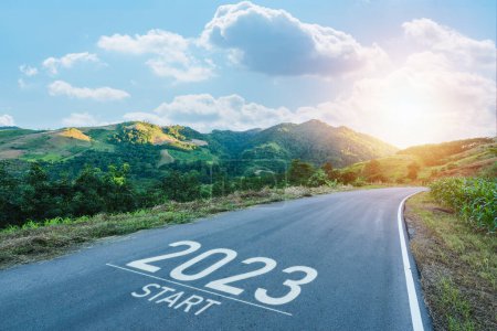 Ein frohes neues Jahr 2023.2023 symbolisiert den Beginn des neuen Jahres. Der Brief Anfang des neuen Jahres 2023 auf der Straße in der Natur Route Fahrbahn Sonnenaufgang haben Baum Umwelt Ökologie oder Grün Tapete Konzept.