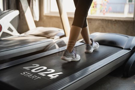 Photo for Happy new year 2024,2024 symbolizes the start of the new year. Close up of feet, sportswoman runner running on treadmill in fitness club. Cardio workout. Healthy lifestyle, guy training in gym. - Royalty Free Image