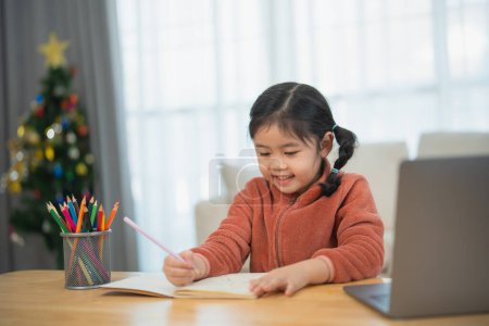 Happy Child Drawing with Color Pencils at Home. A cheerful young girl with pigtails draws contentedly with color pencils, seated at her home desk. Education for kids concept.