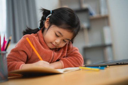 Happy Child Drawing with Color Pencils at Home. A cheerful young girl with pigtails draws contentedly with color pencils, seated at her home desk. Education for kids concept.