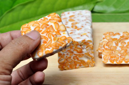 Slice of tempeh on wooden table green leaf background