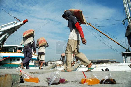 Foto de Yakarta, Indonesia - 29 de mayo de 2010: Los trabajadores transportan cemento de camiones a barcos en el puerto de Sunda Kelapa, Yakarta - Indonesia - Imagen libre de derechos