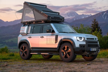 Téléchargez les photos : Land Rover Defender en terrain sauvage, équipé de matériel d'expédition et d'une tente sur le toit - en image libre de droit