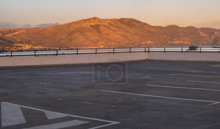 Téléchargez les photos : Parking public en béton avec vue sur les montagnes en arrière-plan le soir - en image libre de droit