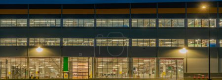 Téléchargez les photos : Façade de l'entrepôt la nuit, vue de l'entrepôt illuminé par les fenêtres - en image libre de droit