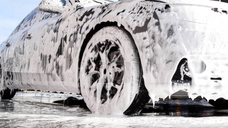 Washing luxury car on a touchless car wash. Washing sedan car with foam and a high pressure water. Spring cleaning in a car wash.