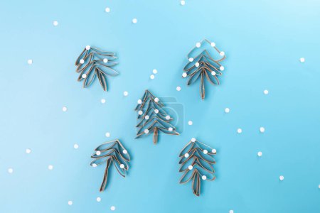 Photo for A paper Christmas tree made out of toilet paper rolls, blue background muted colors with minimalism, craft made of recycle cardboard, DIY, tutorial, educational art for kids, top view - Royalty Free Image