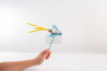 Foto de Mano sostener cohetes de papel artesanía, juguete divertido que hace el proyecto para los niños, bricolaje, paja, fondo blanco - Imagen libre de derechos