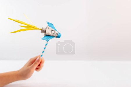 Foto de Un primer plano de una persona sosteniendo un cohete de papel, con un fondo blanco, reciclado, arte de cartón de huevo, fabricación de juguetes divertidos, proyecto para niños, - Imagen libre de derechos