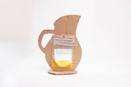 Crafting with cardboard: plastic bag and cutout pitcher assembly, front view, white background, part of craft process