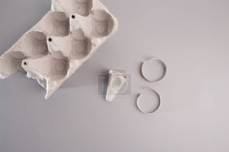 cartón vacío de huevos sentados en la parte superior de una mesa gris, minimalismo, aro de papel, desmontado, cartón, bricolaje, tutorial, parte del proceso de fabricación de la cabeza para la artesanía del carnero de papel