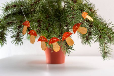 Téléchargez les photos : Décoration de Noël faite à la main à partir de peau de mandarine, concept de nouvelle année, bricolage, artisanat, guirlande en peau de mandarine déshydratée sèche en forme de champignons - en image libre de droit