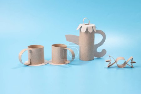 Colorless paper craft, teapot and cups for a doll tea party, embodying recycling concepts. Ideal for DIY crafting with kids.