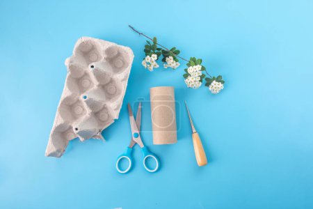 Natural materials for childrens creativity. empty toilet paper roll, egg carton box, white flowers, scissors and awl