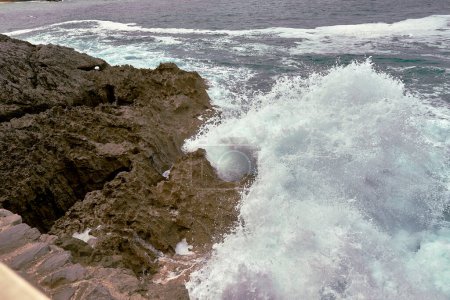 Foto de Olas rompiendo en la orilla en un camino de guijarros. espuma de agua, aguas salvajes, textura, océano, mar, rocas, peligro - Imagen libre de derechos