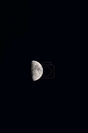 Vertical capture with a telephoto lens showcasing the serene waning moon against the dark, nocturnal sky, evoking celestial tranquility