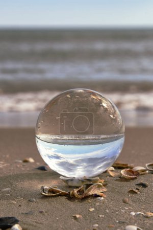 Eine Strandlandschaft auf einer Kristallkugel. Fotografietechniken, Sonne, Wasser, Reflexionen, Muscheln, Wasser, sonnenklarer Himmel