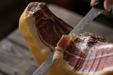 Hand cutting slice of Serrano ham