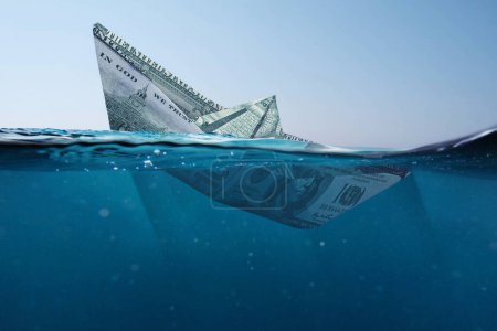 Téléchargez les photos : Concept bateau dollar papier coulant dans la mer avec une vue sous-marine. Finance et crise, une idée créative. Chute des taux de change. Assurances - en image libre de droit