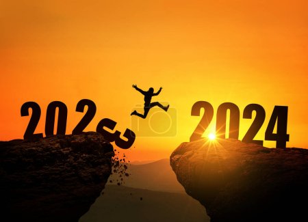Mann springt auf Klippe 2024 über den Abgrund mit Steinen bei erstaunlichem Sonnenuntergang. Neujahrskonzept. 2023 fällt in den Abgrund. Willkommen 2024. Menschen gehen ins Jahr 2024, kreative Idee.
