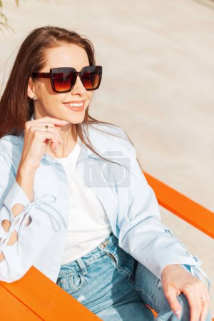 Beautiful happy sunny girl with a smile with vintage sunglasses sets, rest and enjoy on a spring warm day