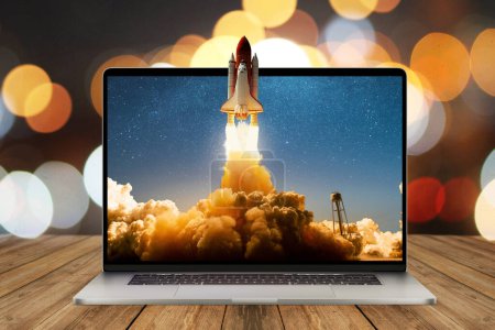 Photo for Space rocket shuttle with a cloud of smoke and blast lift off from a laptop on a working office desk with bokeh. Creative idea and startup. Successful business project. Rocket take off from display - Royalty Free Image
