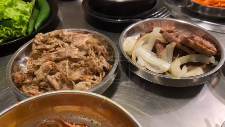 cuencos coreanos de acero inoxidable de los alimentos, incluyendo la carne, cebollas, y otros platos.