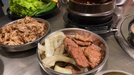 barbacoa coreana o barbacoa carne a la parrilla en tazón de acero inoxidable con cebolla, cubiertos coreanos