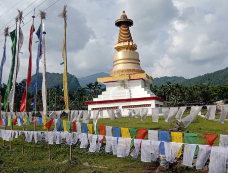 Foto de Coloridas banderas de oración revolotean alrededor de estupas budistas gigantes que se ven fascinantes en Gurobathan en Kalimpong, India. Había un monje desconocido que meditó aquí durante mucho tiempo en los años 90 después de que esta estupa fue construida para recordarle. - Imagen libre de derechos