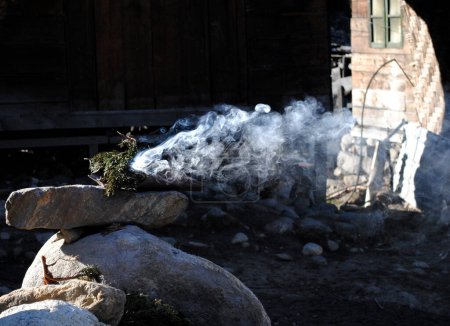 Téléchargez les photos : Une fumée jaillit de l'encens de pin à l'extérieur des maisons purifie les zones du village de Thangu situé à 14000 pieds d'altitude au Sikkim. Le Sikkim est identifié comme un état bouddhiste, de sorte que les drapeaux de prière, les monastères et la fumée de pin sont couramment trouvés ici. - en image libre de droit