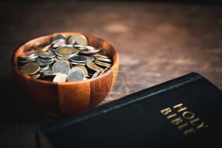 Photo for One tenth or tithe is basis on which Bible teaches us to give one tenth of first fruit to God. coins with Holy Bible. Biblical concept of Christian offering, generosity, and giving tithes in church. - Royalty Free Image